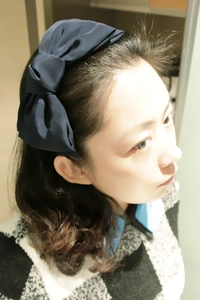 Detailed view of an oversized navy blue satin double bow headband worn by a model