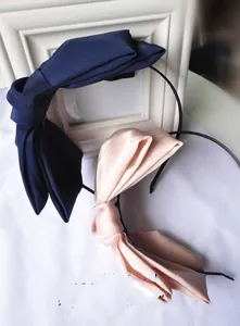 Detail view of oversized satin and matte bow headbands in navy blue and champagne pink