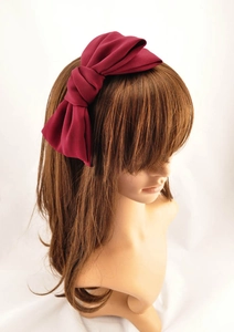 Detail of burgundy satin double-layered oversized bow headband on a display mannequin head