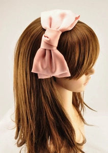 Detail of pink satin double-layered oversized bow headband on brunette hair