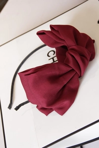 Close-up of vintage burgundy oversized satin double bow headband on a white gift box