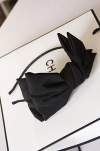 Detail of oversized black satin double-layered bow headband on a stylish gift bag