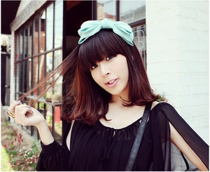 Detailed view of a mint green oversized double-layer satin bow headband on a female model