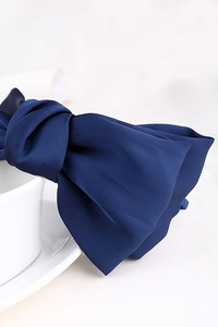 Close-up of navy blue satin double-layered bow headband on a minimalist white background