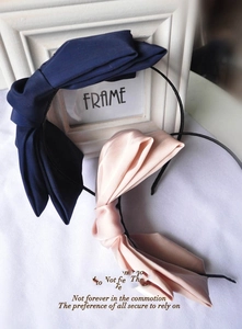 Close-up of double-layer oversized bows in navy twill and pink satin on narrow headbands