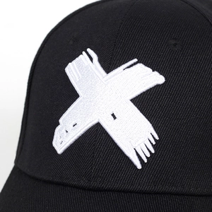 Macro shot of 3D white X-shaped embroidery on a black cotton baseball cap surface