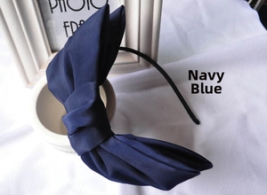 Detail view of navy blue oversized satin double bow headband with elegant fabric texture