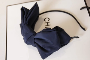 Detail of a large navy blue satin double-layered bow on a slim black headband