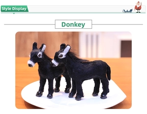 Detailed close-up of realistic fuzzy black donkey figurines in a white tray display