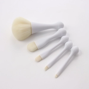 Detailed view of 5 white professional makeup brushes with spiral handles on white background