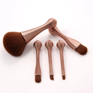 Detailed close-up of 5 portable makeup brushes with rose gold handles and brown bristles