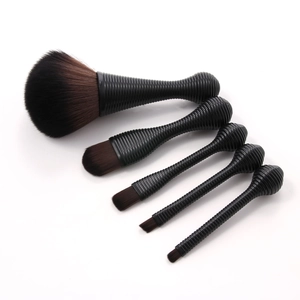 Detailed macro view of 5 professional makeup brushes with black spiral handles and brown bristles