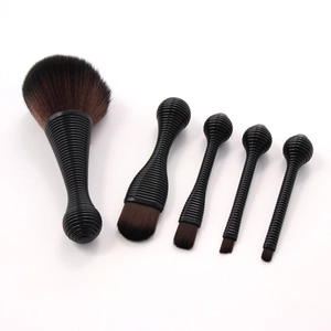 Macro shot of 5 makeup brushes with black threaded handles on a plain white background