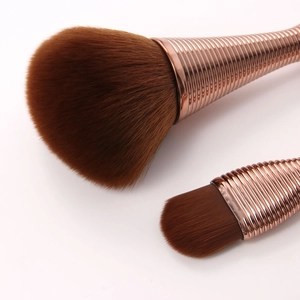 Macro shot of rose gold spiral handles and soft synthetic fibers on professional brushes