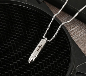 Detailed macro shot of silver bullet cremation pendant necklace with engraved cross icon