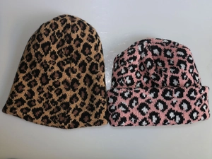Flat lay macro of knitted beanies showing leopard print patterns in brown and pink