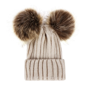 Detailed knit texture of a cream beanie with two large fluffy faux fur pom-poms