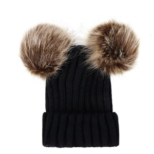 Detail view of black ribbed knit baby beanie featuring two brown faux fur pom-poms