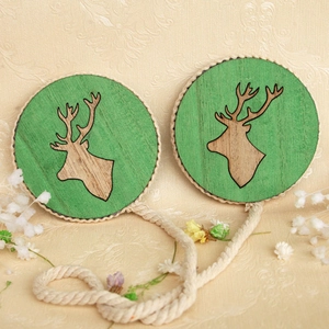 Detail of wooden curtain tiebacks with green deer silhouette and rustic hemp rope