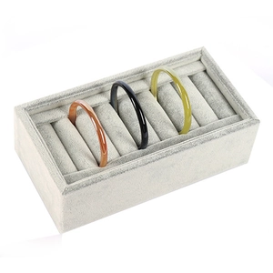 Gray velvet jewelry display tray showcasing multiple bracelets from a professional 45-degree angle