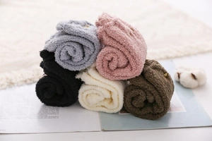 Close-up of five pairs of thick coral fleece socks in soft pastel colors and warm texture