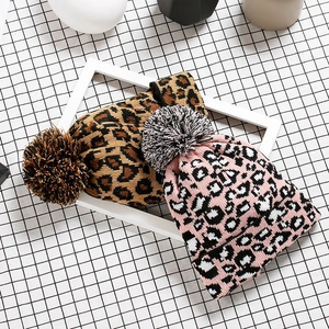 Winter leopard print knit beanies with fluffy pom poms in brown and pink colors
