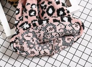 Detailed close-up of thick pink leopard knit texture and fold of a winter beanie