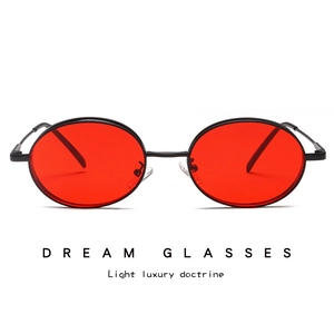 Detail of vintage oval sunglasses featuring slim black metal frames and red tinted lenses