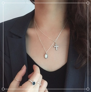 Close-up of double layer S925 silver necklace with oval gem and cross pendant on a model