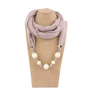 Detail of beige ethnic scarf necklace with large cream beads and silver metal accents