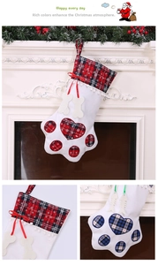 Detail of paw-shaped Christmas stockings with plaid patterns and bone charms on fireplace