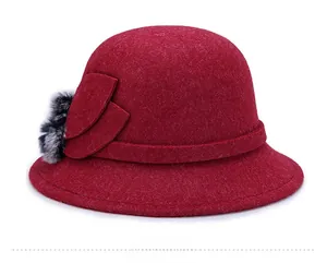 Dettaglio cappello cloche in lana bordeaux con petali floreali e pompon in pelliccia
