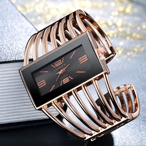 Macro detail of hollow rose gold bangle watch featuring a black rectangular dial