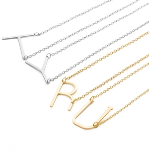 Detail of gold and silver initial letter pendants T, Y, R, U with polished metal finish