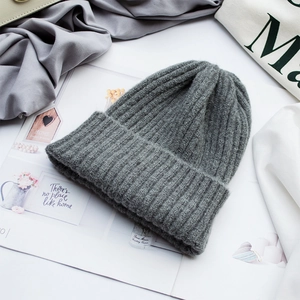 Detailansicht der dunkelgrauen Strickmütze mit weicher Rippstruktur auf Magazinuntergrund