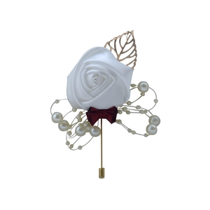 Detailed view of white satin rose brooch with dark red bow and artificial pearls