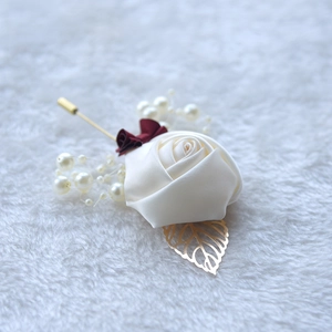 Detailed macro view of ivory satin rose boutonniere with gold leaves and pearl accents
