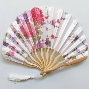 Close-up of Japanese silk folding fan with pink floral peony patterns and bamboo ribs