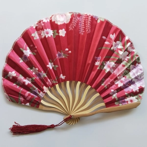 Detail of red silk folding fan with Japanese floral patterns and a red silk tassel