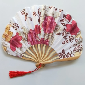 Close-up of Japanese style folding fan featuring pink floral patterns and red tassel