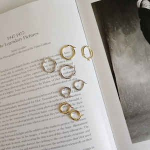 Polished silver and gold hoop earrings in various sizes on a minimalist magazine page
