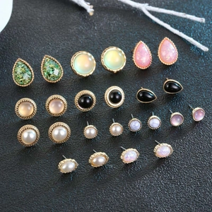 Close-up of pearl, opal, and black gem stud earring set in gold metal frames