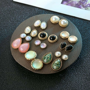 Vintage gold earring set featuring cat eye resin, pearls, and colorful gemstones