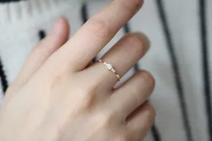 Macro detail of slim gold ring featuring seven small diamonds worn on the index finger