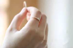 Detailed close-up of slim 14K gold plated silver ring with tiny diamonds on a finger