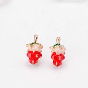Close-up of strawberry stud earrings with red enamel and green leaves on gold alloy