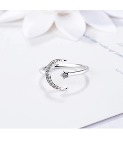 Close-up of adjustable silver moon and star ring with sparkling crystals and floral accent