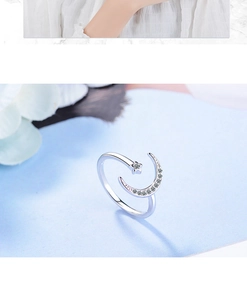 Close-up of silver moon and star open ring with sparkling crystals on blue background