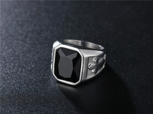 Detailed close-up of a vintage men's ring with a black gemstone and silver cross relief