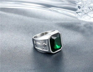 Macro shot of silver signet ring with green emerald-cut stone and cross pattern